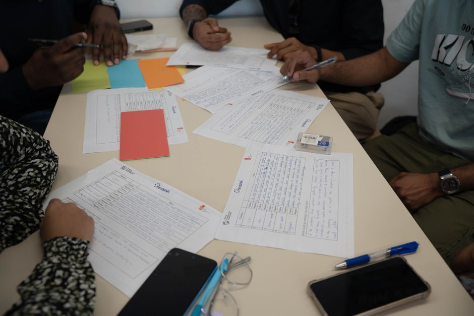 A diverse team working together, reviewing documents and making notes during a collaborative meeting.