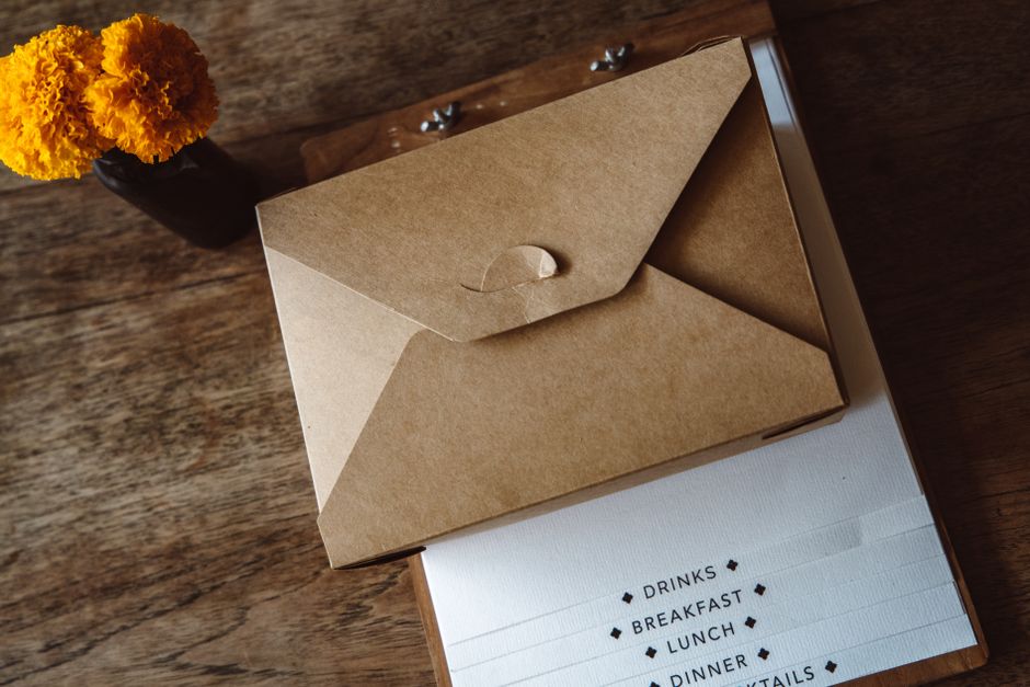 Brown envelope and clipboard on a wooden table with marigold flowers, offering a vintage and cozy ambiance.