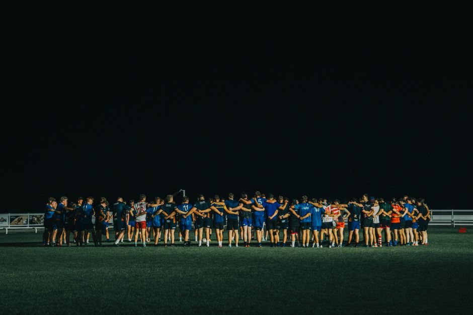 Sports team huddle on a field at night, fostering teamwork and unity.